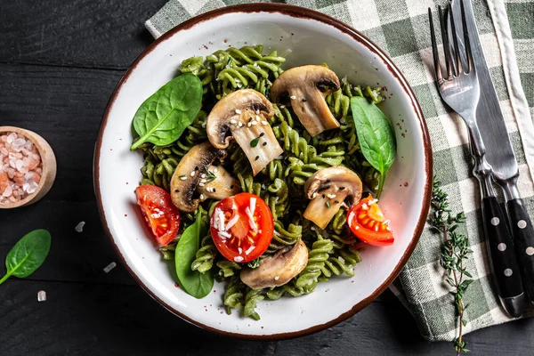 Ispanaklı vejetaryen makarna, mantar mantarı, vişneli domates. Vegan gıda konsepti. en üstteki görünüm.