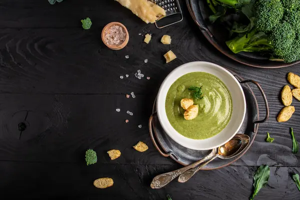 Traditional recipe of broccoli cheese soup with vegetables in a bowl with toast, homemade healthy organic vegetarian vegan diet fresh food meal dish soup lunch, space for text. top view.