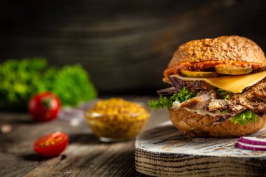 Köy masasında sığır etli, peynirli ve sebzeli hamburger. Fast food ve abur cubur konsepti. Boşluğu kopyala.