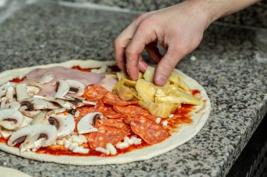 Pizza yapma süreci. Eller pizza hazırlıyor. Mutfakta pizza yapan aşçının yakın çekimi..
