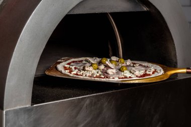 Chef taking raw pizza on metal shovel. Restaurant chef takes pizza from oven in traditional restaurant. Preparing traditional italian pizza.