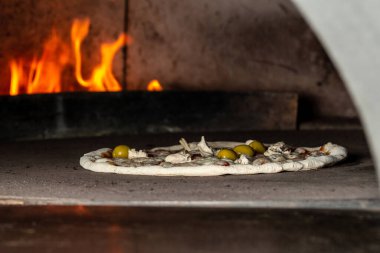 Baked pizza in the front of the oven in traditional restaurant. Preparing traditional italian pizza.