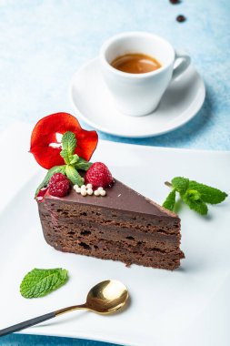 Lezzetli çikolatalı kek tabakta bir fincan kahve mavi arka planda, dikey görüntü, metin için yer.