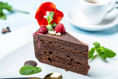 Naneli bir parça çikolatalı kek, mavi arka planda bir fincan kahve..