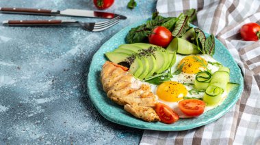Kirazlı yumurta, avokado, ızgara tavuk fileto, salatalık ve avokado. Ketogenik diyet kahvaltısı. metin için yer, üst görünüm.