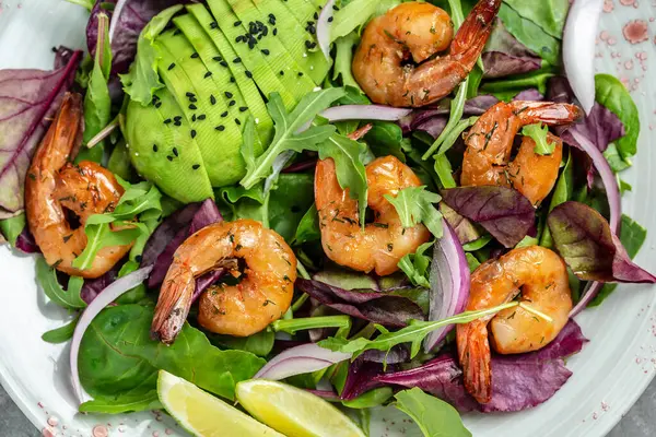 Green salad with avocado and shrimps salad. Seafood concept. Tasty veg mixed leaves, grilled prawn shrimps. Healthy food. Clean eating. Food recipe background. Close up.