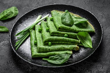 Lezzetli ıspanak krepleri siyah tabakta sebzeli yeşil krep, koyu arka plan, yemek tarifi geçmişi. Kapat.,