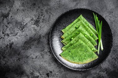 Koyu arkaplanda ıspanak yeşili krep. Lezzetli sağlıklı kahvaltı. Vejetaryen yemekleri, üst manzara..