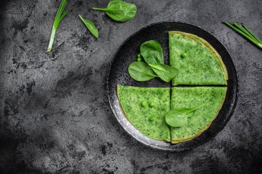 Siyah tabakta ıspanaklı yeşil vejetaryen krepleri, koyu arka plan, sağlıklı kahvaltı, vejetaryen yemekleri, üst manzara..