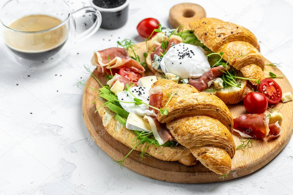 morning poached egg with prosciutto, poached egg, jamon, blue, cheese, avocado, microgin and cherry tomatoes on a light background, Cup of coffee.