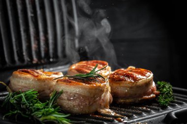 Izgarada biftek pişiriyorum. Domuz pastırmasına sarılı sığır filetosu bifteği. Fileminyon. biber dondurucu bir hareketle,