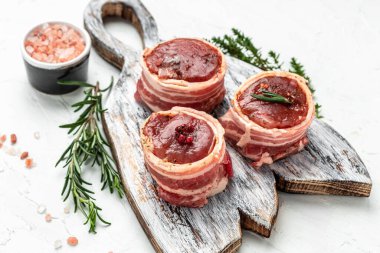 Çiğ biftek fileto domuz pastırmasına sarılıp tahta tahtaya sarmalanmış hafif arka plan, fileto Mignon. en üstteki görünüm.