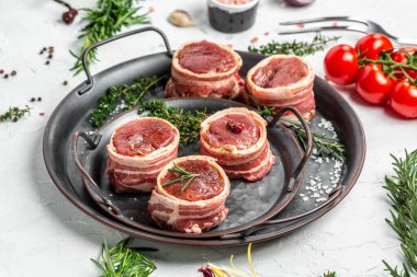 Taze domuz eti pişmeye hazır. Domuz pastırmasına sarılı sığır fileto bifteği hafif arka planda eski et tepsisi, fileto Mignon. en üstteki görünüm.