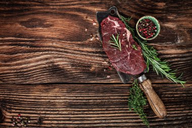 Biber biberiyeli çiğ biftek ve siyah ahşap arka planda eski et satırı. afiş, metin için menü tarifi yeri, üst görünüm.