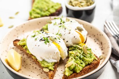 Avokadolu kahvaltı tostu, haşlanmış yumurta, lezzetli kahvaltı ya da hafif arka planda atıştırmalık, üst manzara.,