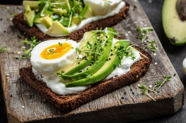 Avokado ve yumurtalı sandviç. Sağlıklı kahvaltı ya da atıştırmalık için tam ekmekli tost dilimlenmiş avokado ve yumurta..