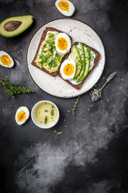 Haşlanmış yumurtalı avokado sandviçi ve mısır gevreği ekmeğinde yumuşak peynir. dikey resim yemek tarifi arkaplanı. Kapat..