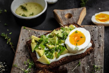 Taze yeşil avokado, yumurta ve gevrek ekmekli yumuşak peynirli sandviç. Yemek tarifi geçmişi. Kapat..