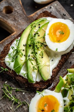 Taze yeşil avokado, yumurta ve gevrek ekmekli yumuşak peynirli sandviç. dikey Resim Üst Görünüm