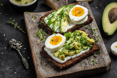 Avokado, yumurta ve mısır gevreği ekmeğinde yumuşak peynirli tost. Yemek tarifi geçmişi. Kapatın. rustik ahşap arkaplan.