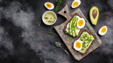 Sağlıklı kepekli sandviç, avokado, yumurta ve mısır gevreği ekmeğinde yumuşak peynir. Pankart, menü, tarif, mesaj için yer. Üst görünüm.