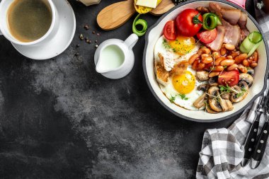 İngiliz kahvaltısı yumurta, fasulye, domates, pastırma ve kızarmış tavada ekmek. Üst görünüm.