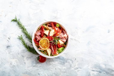 Prosciutto salatası, jambon ve greyfurt jamonu, salata karışımı, greyfurt, vişneli domates, parmesan peyniri. Paket paket veya yiyecek teslimatı için. metin için yer, üst görünüm.