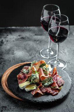Koyu arka planda farklı antipasti içeren kırmızı şarap. dikey resim, metin için yer.