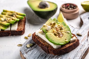 Sağlıklı avokado tostları, çavdar ekmeği dilimlenmiş avokado, peynir, balkabağı, fındık ve susamlı kahvaltı ya da öğle yemeği. Vejetaryen yemeği. Vejetaryen menüsü. Yemek tarifi geçmişi. Kapat..