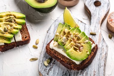 Kahvaltıda ya da öğle yemeğinde fındık ve susamlı avokado ve peynirli iki tost. Vejetaryen yemeği. Temiz yemek. Üst Manzara. Boşluğu kopyala.
