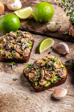 Avokado tostu, mantar ve mikroyeşil tam tahıllı sandviç. Susam ile süslenmiş. Vejetaryen yemeği. Vejetaryen menüsü. dikey resim, metin için yer.