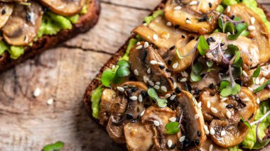 Avokado tostu, mantar ve mikroyeşil tam tahıllı sandviç. Susam ile süslenmiş. Vejetaryen yemeği. Vejetaryen menüsü. Yemek tarifi geçmişi. Kapat..