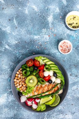 Tavuk fileto, avokado, kuşkonmaz, nohut, brokoli, turp, salatalık zeytinli mozzarella soslu Buda tabağı. Sağlıklı dengeli beslenme. dikey resim.