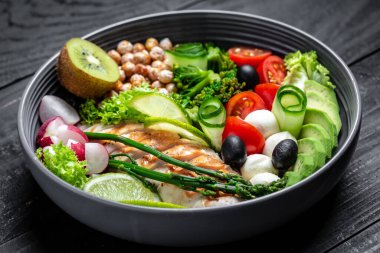 Izgara tavuk, avokado, kuşkonmaz, nohut, brokoli, turp, tavuk, salatalık, domates zeytinli mozzarella Buddha kasesi koyu arkaplama, üst manzara. Lezzetli dengeli gıda konsepti,