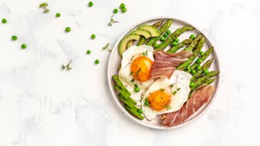 Tavada kızarmış yumurta, avokado ve prosciutto ile yeşil kuşkonmaz. Ketogenik diyet öğle yemeği konsepti. menü, üst görünüm.