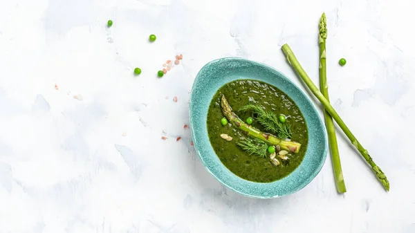 Asparagus soup, green soup, Spring detox cream soup in bowls. Clean eating, dieting, vegan, vegetarian, healthy food concept. Long banner format, top view.