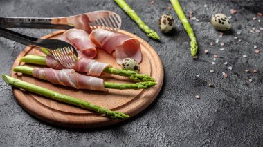 Kuşkonmaz ve pastırma pişirmeye hazır. Kuşkonmaz ve pastırma. Parma jambonuna sarılmış kuşkonmaz..