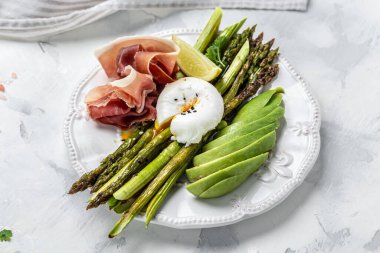 Keto kahvaltısı. Haşlanmış yumurta, avokado, prosciutto, jamon ve pastırmalı kuşkonmaz. Düşük karbonhidratlı yüksek yağlı kahvaltı. Üst görünüm.