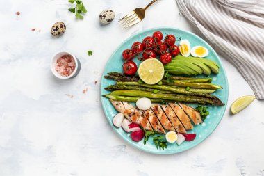 Keto diyet yemekli tabak. kuşkonmaz, tavuk fileto, vişneli domates, avokado, bıldırcın yumurtası ve turp siyah masada servis edilir. Keto kahvaltısı. Pankart, üst görünüm.