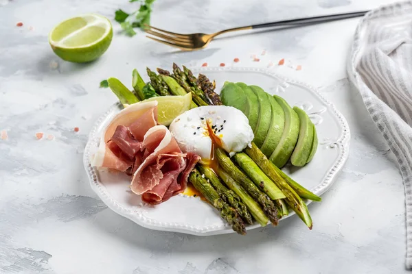 breakfast baked asparagus with Poached Egg, avocado and prosciutto, jamon, bacon. Low carb high fat breakfast. Keto breakfast. Brunch. Top view,