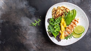 Buda kasesi, ızgara tavuk göğsü, halloumi, ananas, avokado, yeşil roket salatası, limon ve zeytinyağı. sağlıklı ve dengeli yiyecekler. afiş, metin için menü tarifi yeri, üst görünüm.