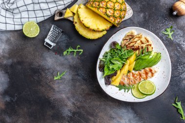 Ananas salatalı Buda kasesi, ızgara tavuk göğsü, halloumi, avokado, yeşil roket salatası, limon ve zeytinyağı, susam ve tohumlar. afiş, metin için menü tarifi yeri, üst görünüm.