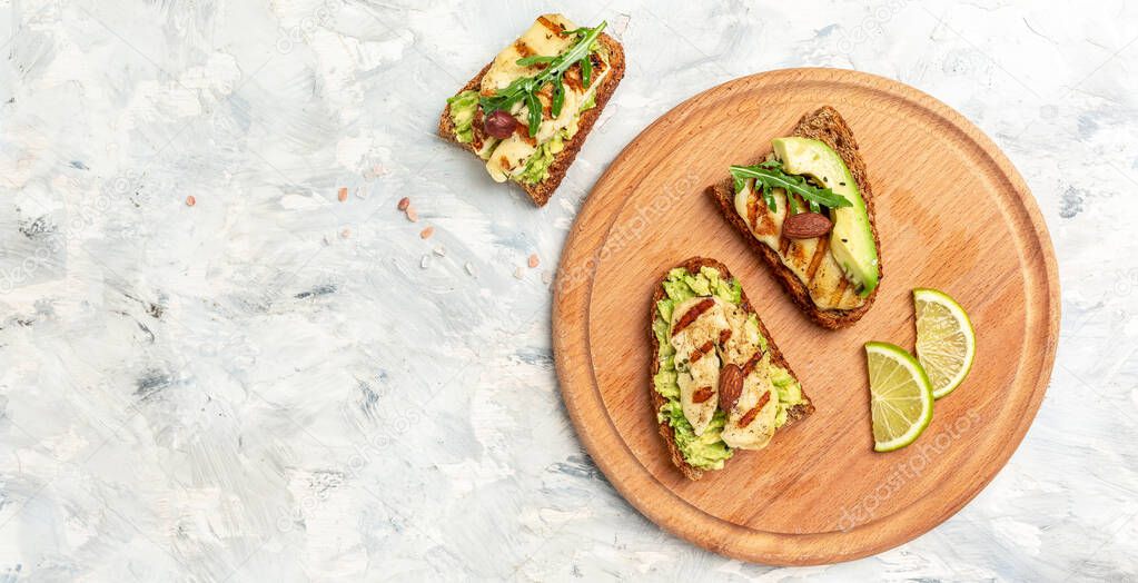 Bruschetta, toasted grilled Halloumi cheese and slices of avocado guacamole on white background top view with space for text. Healthy food. Long banner format