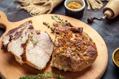 Kesme tahtasının üzerinde kekik hardalıyla dilimlenmiş domuz rostosu. Restoran menüsü, diyet, yemek kitabı tarifi..