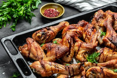 Fırında tavuk kanadı ve yemek tepsisinde bacaklar. Koyu taş masada barbekü kanatları. Üst manzara, yemek tarifi geçmişi. Kapat.,