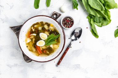 Beyaz masada kaynamış bıldırcın yumurtası ve ekşi kremalı yeşil kuş çorbası, Skabenu zupa Letonya çorbası, üst manzara.,