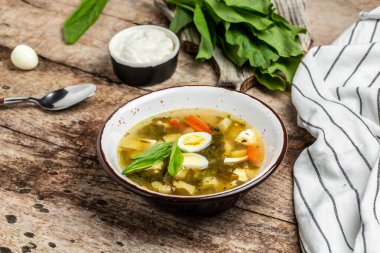 Beyaz bir kasede kuş çorbası, kaynamış bıldırcın yumurtası ve ahşap bir masada ekşi krema. Yemek tarifi geçmişi. Kapat, üst görünüm.