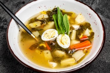 Yumurtalı diyet kuş çorbası, kasede. Yumurtalı, patatesli, havuçlu, maydanozlu kuş çorbası. Uzun afiş biçimi. en üstteki görünüm.