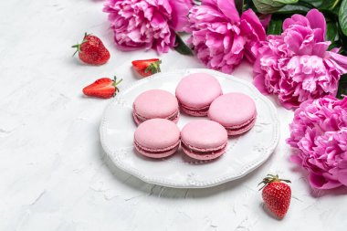 Pink peonies with French cakes Macarons with fruit on white background. French delicate dessert for Breakfast in the morning light.