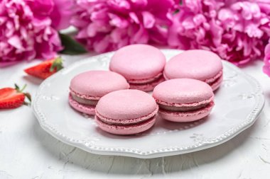 Elegant sweet macarons and Pink peony rose flowers, French delicate dessert for Breakfast in the morning light .